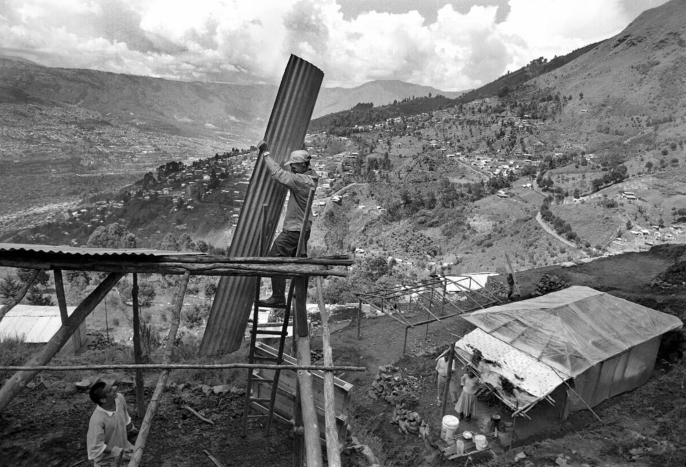Vista en blanco y negro del barrio La Honda en la ladera de Medellín, con ranchos de madera